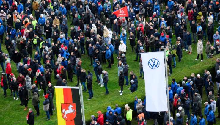 Persone camminano su un prato, bandiere di Germania e Volkswagen