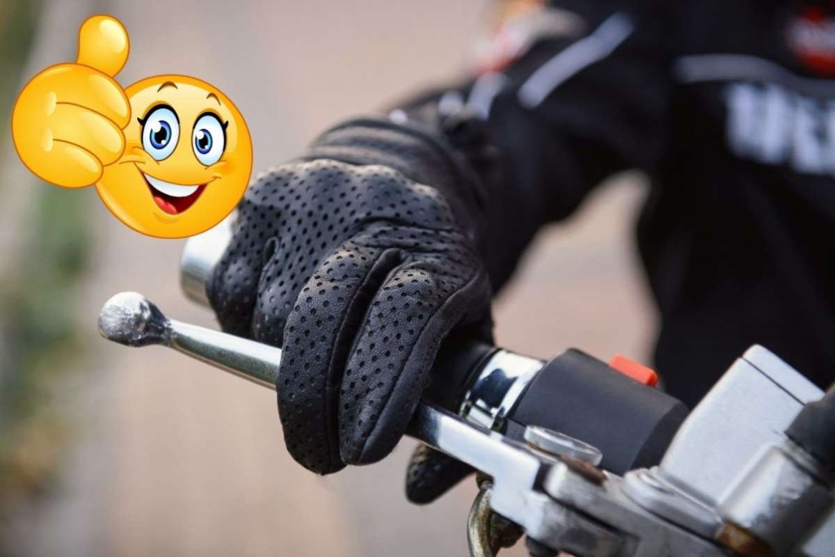 Una mano sul manubrio di uno scooter ein alto a sinistra un emoticon con il pollice su