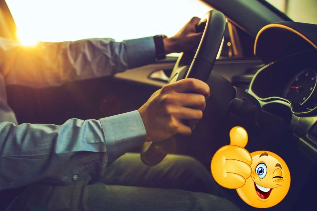 una persona al volante di un'auto e in basso a destra l'emoticon con il pollice su