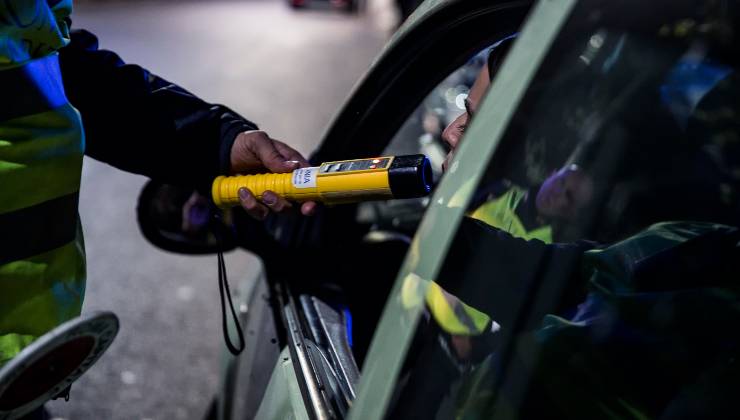 Un poliziotto effettua la prova dell'etilometro ad un uomo seduto in auto