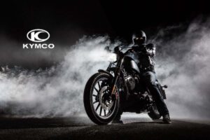 Il logo Kymco e una persona con tuta e casco neri in sella ad una moto nera