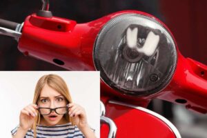 Il manubrio di una Vespa e in basso a sinistra una donna sorpresa