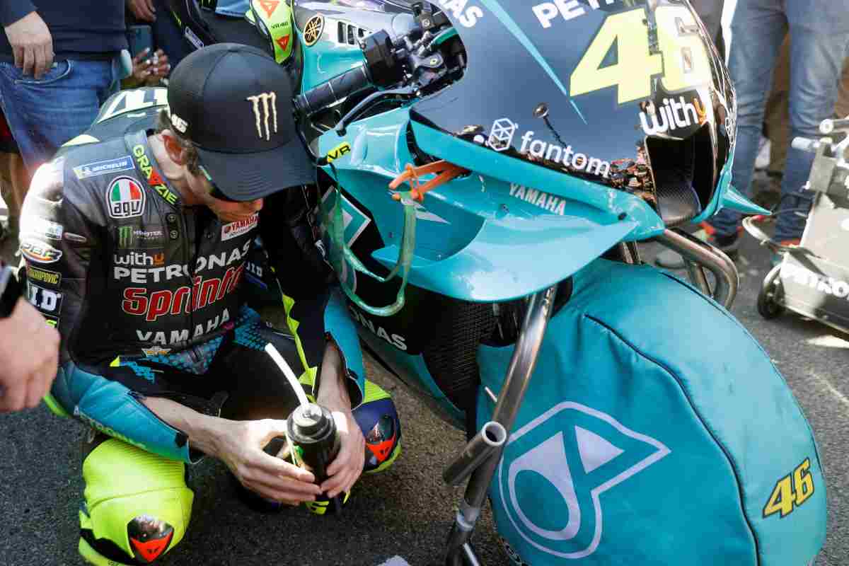 Valentino Rossi accucciato a fianco della sua moto