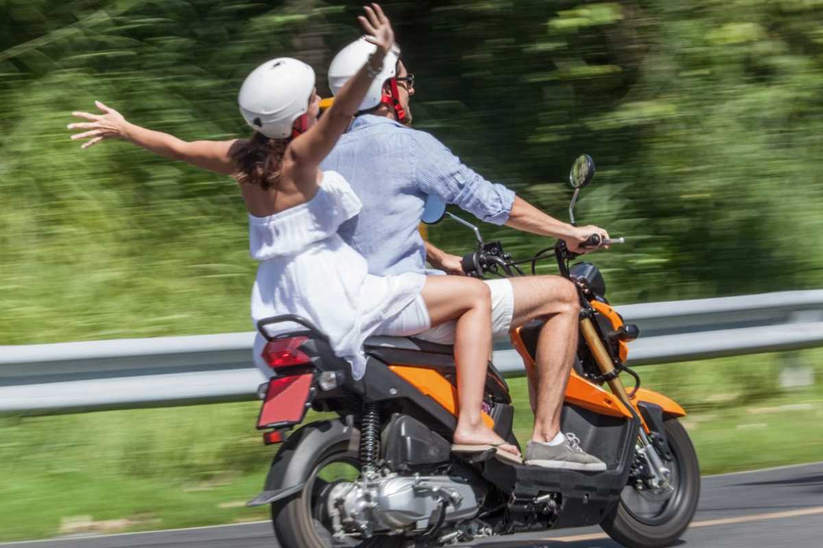 Due persone su uno scooter in una strada extraurbana