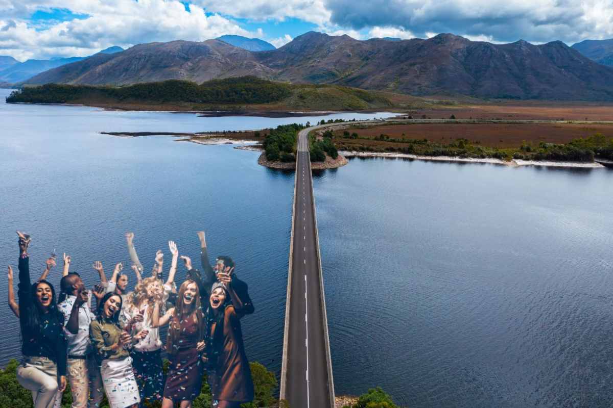 Una strada attraversa un lago, a sinistra un gruppo di persone festeggia