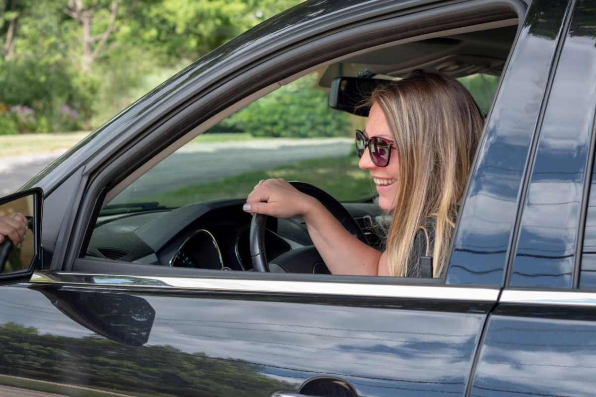 Una donna con gli occhiali da sole al volante